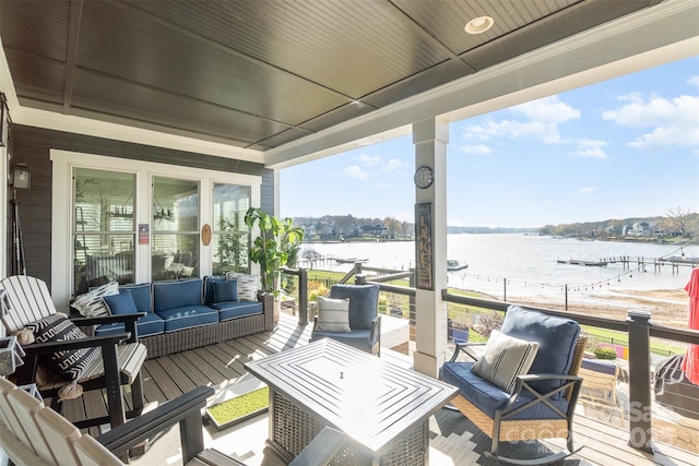 wooden deck featuring an outdoor living space and a water view