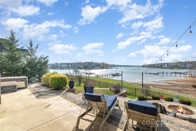 view of patio / terrace featuring a water view, an outdoor fire pit, and a hot tub