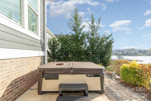 view of patio / terrace featuring a hot tub and a water view