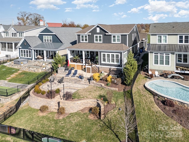 rear view of house with a fenced in pool and a lawn