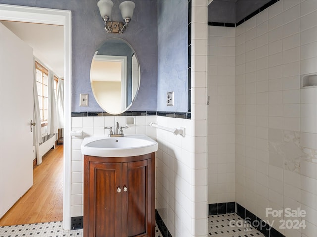 bathroom featuring radiator heating unit, vanity, tile walls, and hardwood / wood-style flooring