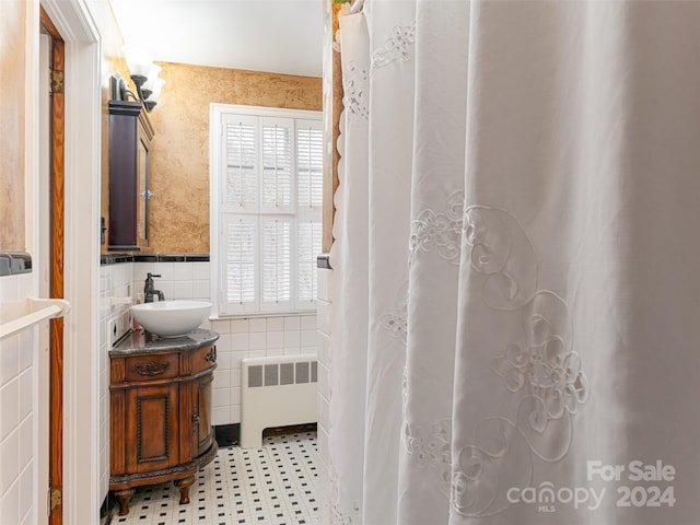 bathroom featuring radiator heating unit, vanity, tile walls, and a healthy amount of sunlight