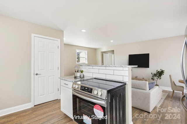 kitchen featuring light stone countertops, light hardwood / wood-style flooring, white cabinets, and stainless steel range with electric stovetop