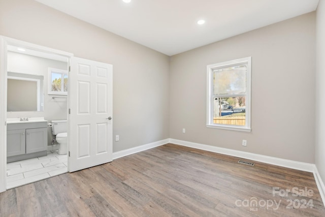 unfurnished bedroom with ensuite bath, light hardwood / wood-style flooring, and sink