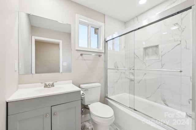 full bathroom featuring vanity, toilet, and bath / shower combo with glass door