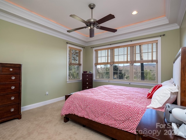 carpeted bedroom with a tray ceiling, ceiling fan, and ornamental molding