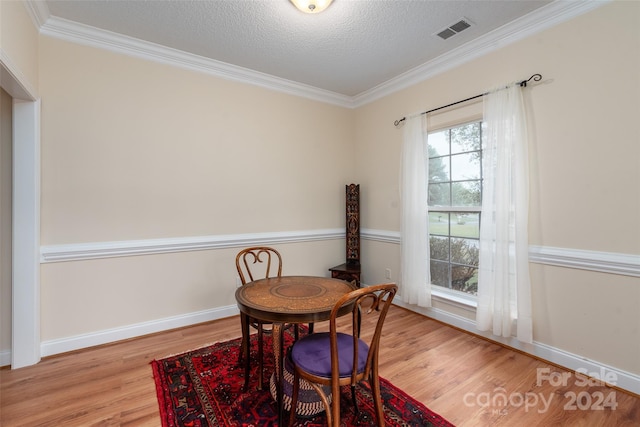 dining space featuring a textured ceiling, light hardwood / wood-style floors, and crown molding