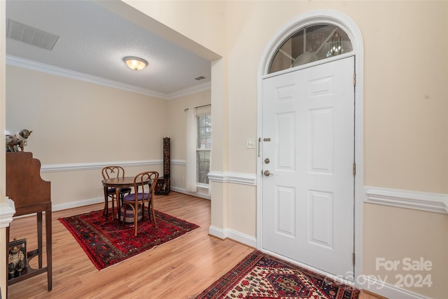 foyer entrance with hardwood / wood-style floors, crown molding, and a textured ceiling