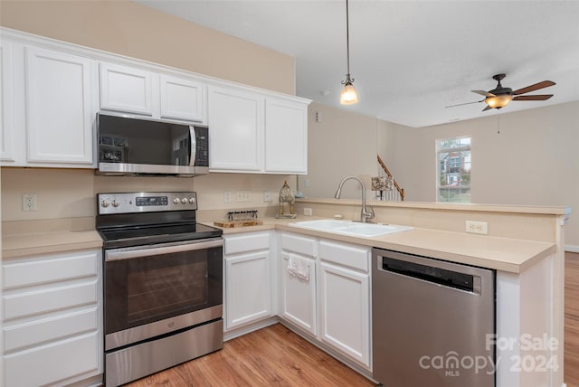 kitchen with kitchen peninsula, appliances with stainless steel finishes, sink, light hardwood / wood-style floors, and white cabinetry