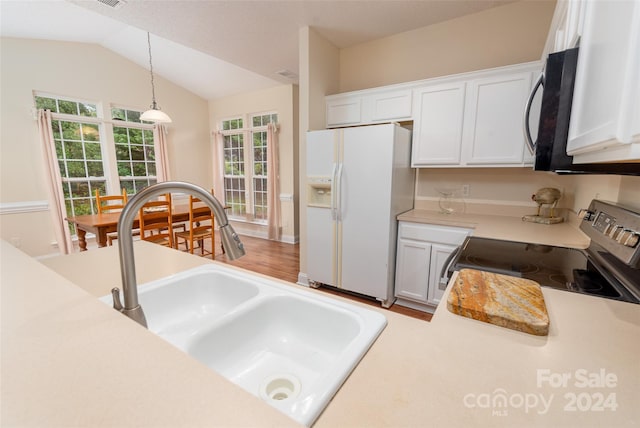 kitchen with stainless steel stove, white refrigerator with ice dispenser, pendant lighting, lofted ceiling, and white cabinets