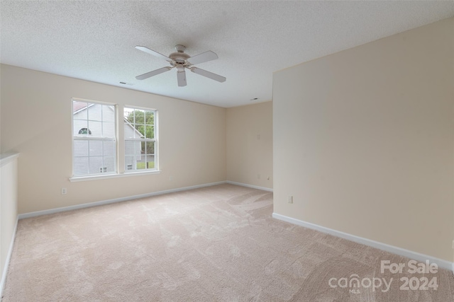 unfurnished room featuring light carpet, ceiling fan, and a textured ceiling