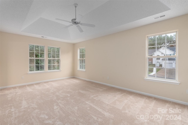 carpeted empty room featuring ceiling fan, a textured ceiling, and a tray ceiling