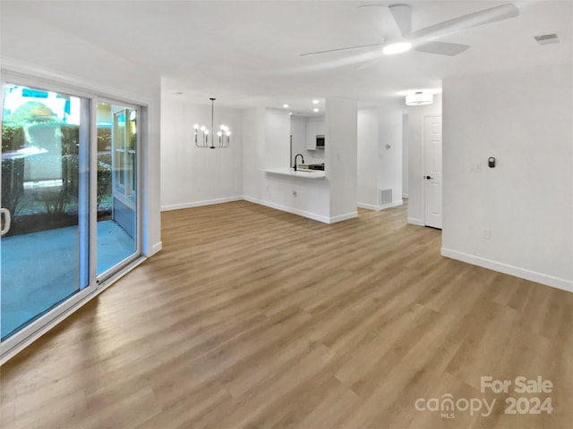 unfurnished living room with ceiling fan with notable chandelier, sink, and light hardwood / wood-style flooring