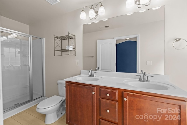 bathroom featuring tile patterned flooring, vanity, toilet, and a shower with door