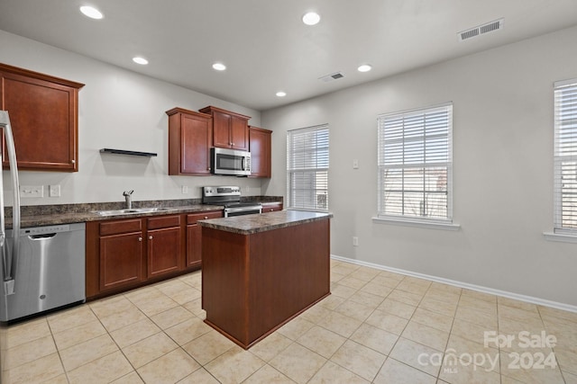 kitchen with sink, a center island, light tile patterned flooring, and appliances with stainless steel finishes