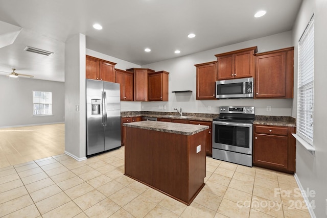 kitchen with ceiling fan, sink, stainless steel appliances, light tile patterned floors, and a kitchen island