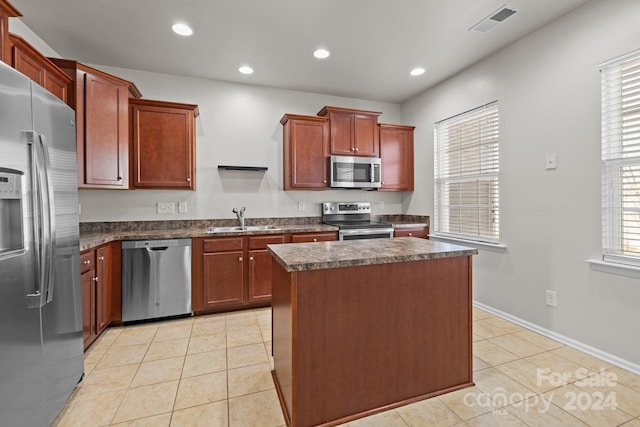 kitchen with a center island, light tile patterned floors, stainless steel appliances, and sink