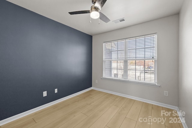 empty room featuring ceiling fan, plenty of natural light, and light wood-type flooring