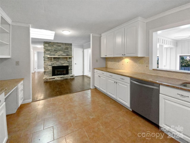 kitchen featuring backsplash, a fireplace, ornamental molding, dishwasher, and white cabinetry