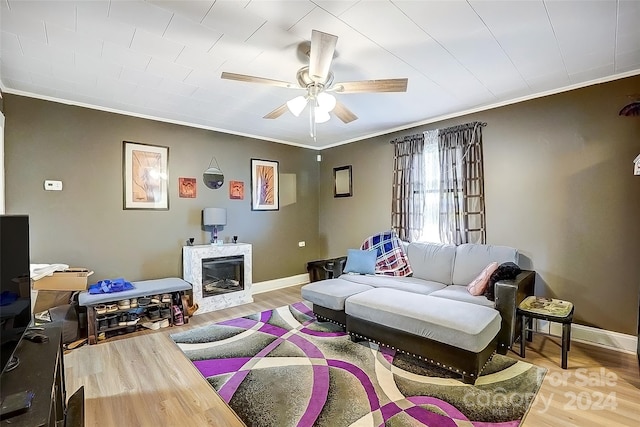 living room with ceiling fan, a fireplace, ornamental molding, and hardwood / wood-style flooring