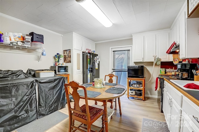 kitchen with white cabinets, ornamental molding, stainless steel appliances, and light hardwood / wood-style floors