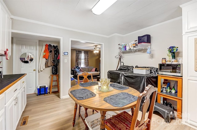 dining space with ceiling fan, ornamental molding, and light wood-type flooring