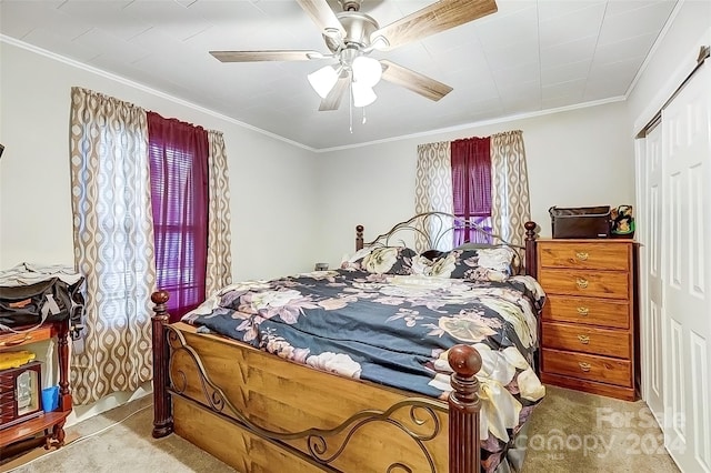 carpeted bedroom with ceiling fan, ornamental molding, and a closet