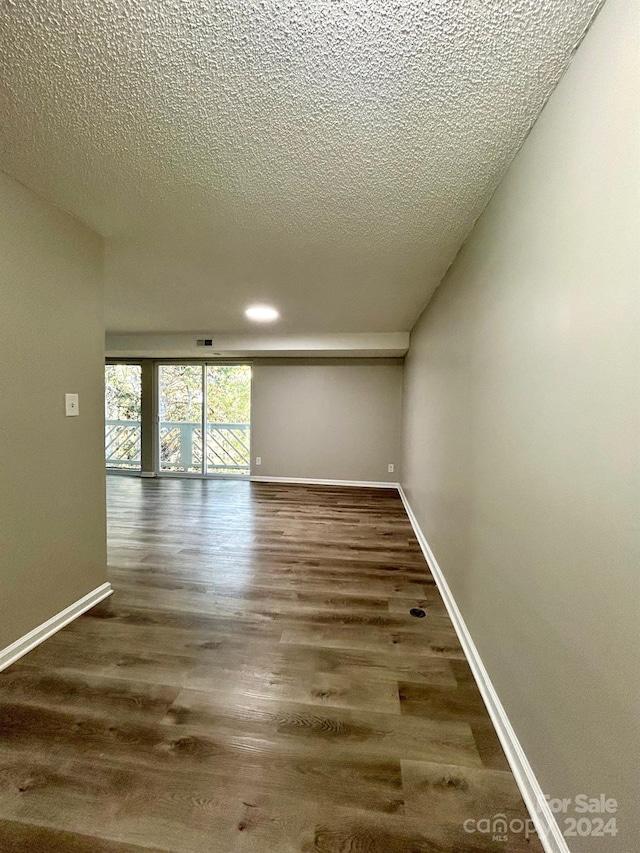 spare room featuring dark wood-type flooring and a textured ceiling