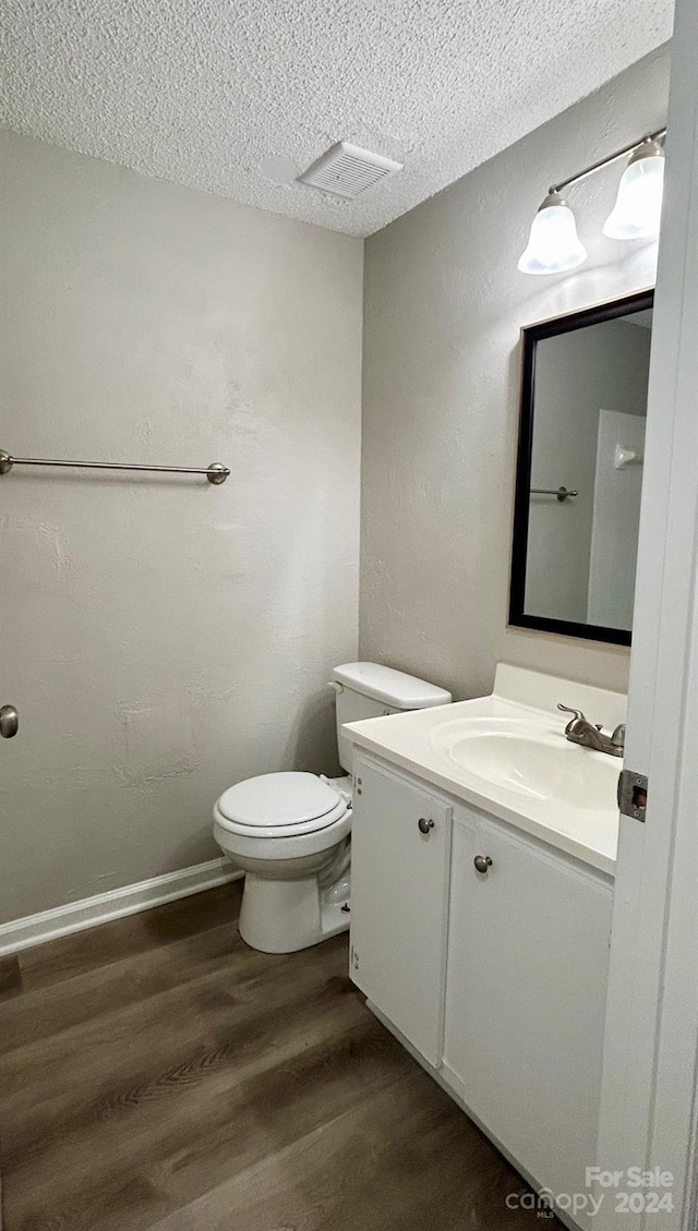 bathroom featuring vanity, toilet, wood-type flooring, and a textured ceiling