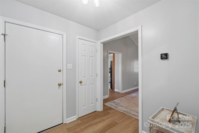 entryway with a textured ceiling and light hardwood / wood-style flooring