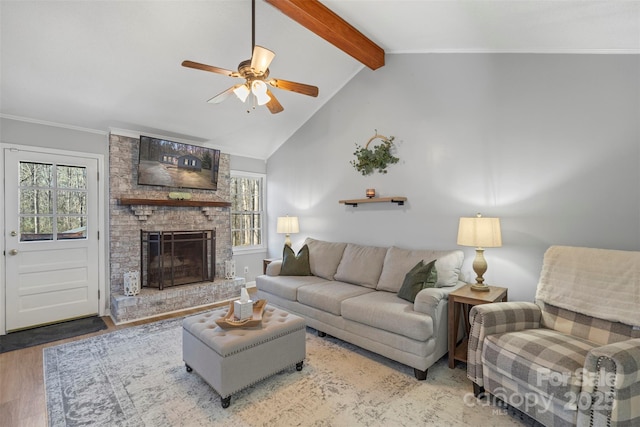 living room with a wealth of natural light, wood-type flooring, a large fireplace, and lofted ceiling with beams