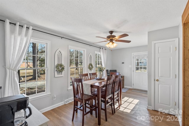 dining space featuring ceiling fan, a textured ceiling, and light hardwood / wood-style flooring