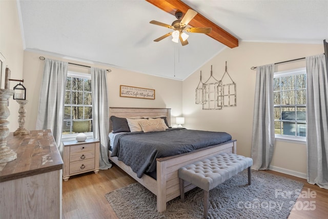 bedroom featuring ceiling fan, light hardwood / wood-style floors, multiple windows, and lofted ceiling with beams