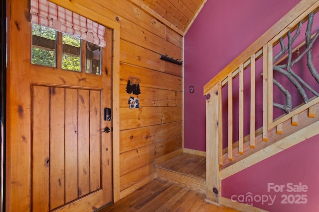 staircase featuring hardwood / wood-style floors, vaulted ceiling, and wood walls