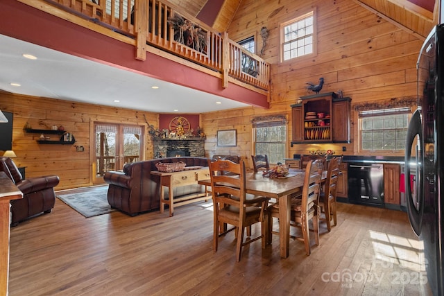 dining room with hardwood / wood-style flooring, plenty of natural light, and wood walls