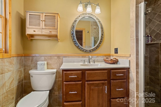 bathroom featuring vanity, toilet, a shower with door, and tile walls