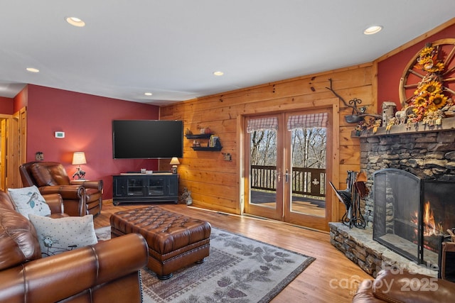 living room featuring wooden walls, a fireplace, and light wood-type flooring