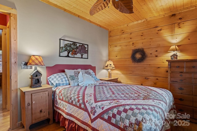 bedroom with ceiling fan, wood walls, wood-type flooring, and wooden ceiling