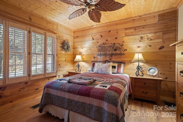 bedroom with ceiling fan, wooden walls, wooden ceiling, and light hardwood / wood-style floors