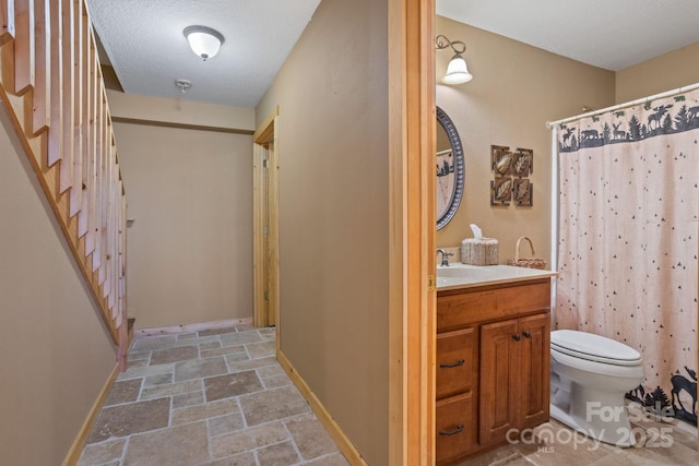 bathroom featuring vanity, toilet, a textured ceiling, and walk in shower