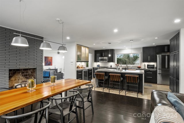 kitchen featuring pendant lighting, a center island, light hardwood / wood-style flooring, a fireplace, and stainless steel appliances