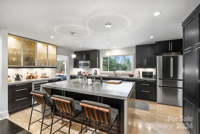 kitchen with pendant lighting, a center island with sink, a kitchen breakfast bar, light hardwood / wood-style floors, and stainless steel appliances