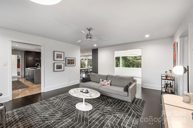 living room featuring ceiling fan, sink, and dark wood-type flooring