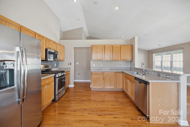 kitchen featuring kitchen peninsula, appliances with stainless steel finishes, sink, light brown cabinets, and light hardwood / wood-style flooring