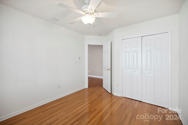 unfurnished bedroom with hardwood / wood-style floors, a closet, and ceiling fan