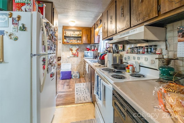 kitchen with tasteful backsplash, light hardwood / wood-style floors, and white appliances