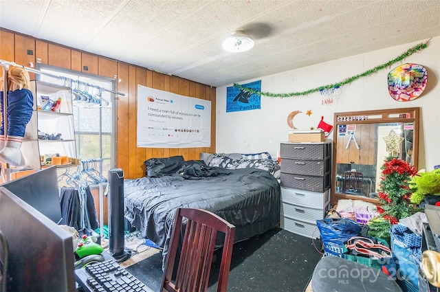 bedroom with dark colored carpet and wooden walls