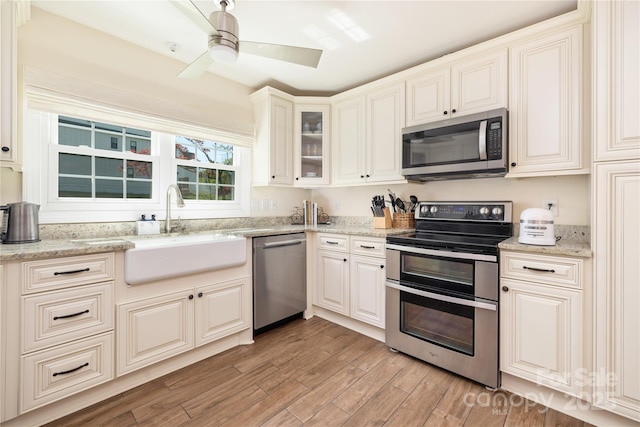 5431 Park Rd, Charlotte, NC 28209 - kitchen featuring light stone counters, a ceiling fan, appliances with stainless steel finishes, light wood finished floors, and a sink
