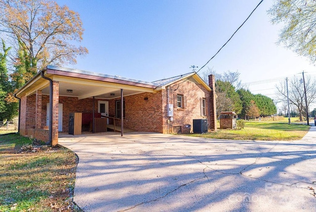 view of front of house featuring cooling unit, a front yard, and a carport