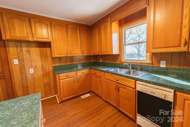 kitchen with dishwasher, wood walls, crown molding, sink, and light hardwood / wood-style floors